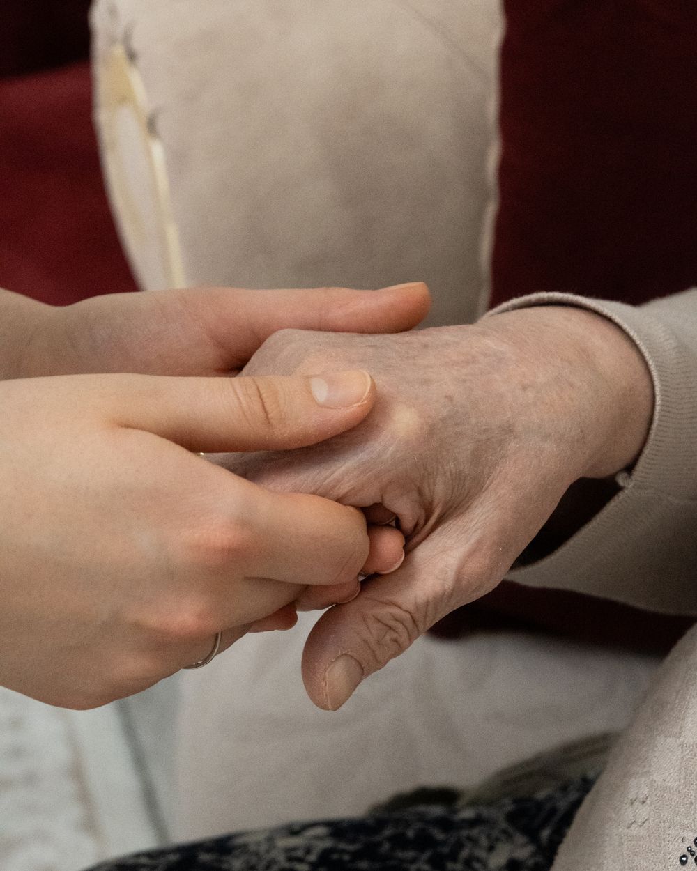 A younger person's hands gently holding an older person's hand.